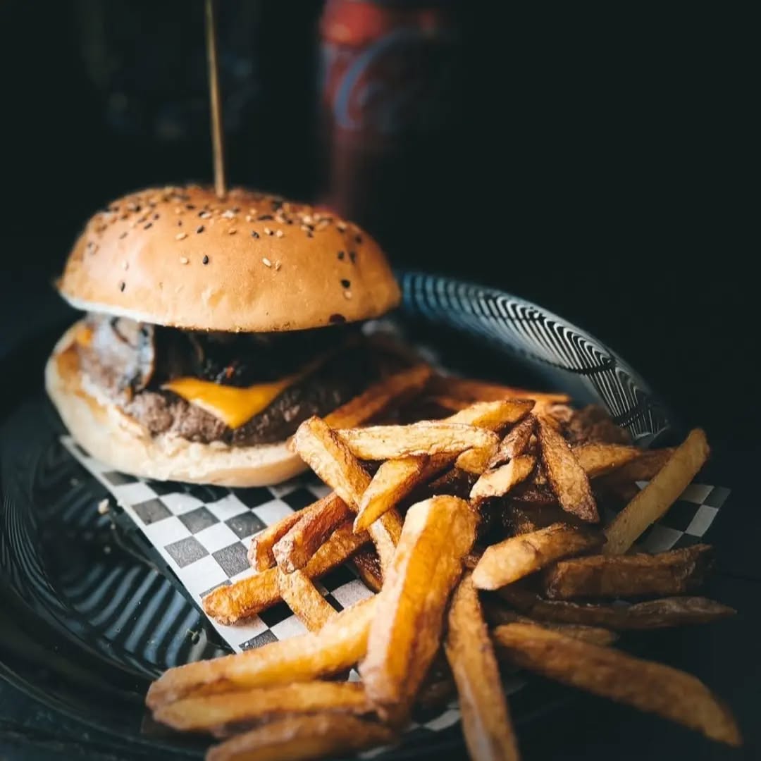 Hamburguesa artesanal con papas fritas servida en Kochü, restaurante en Vichuquén con vista al Lago